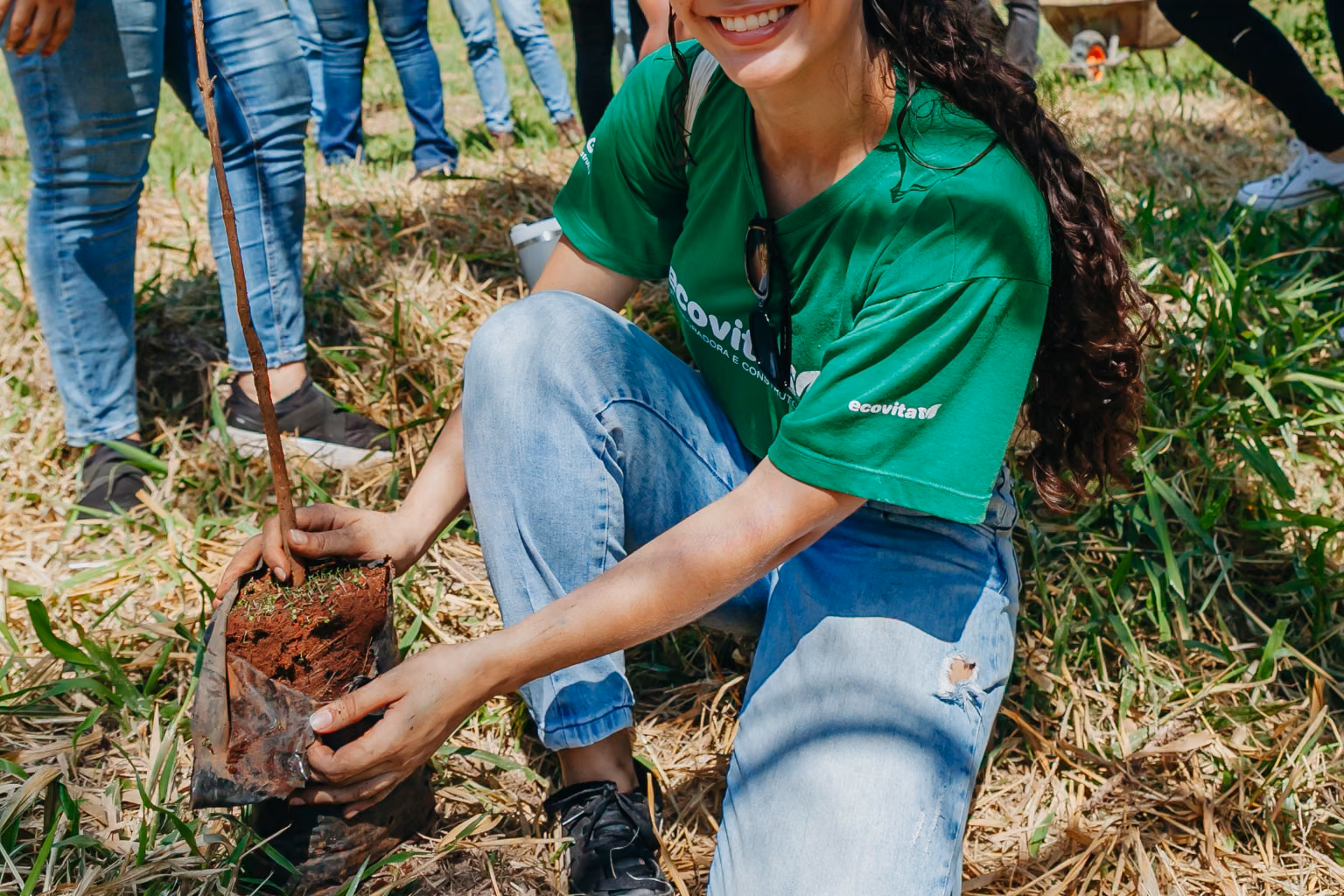 Participante sorridente mostrando as mãos com terra após o plantio